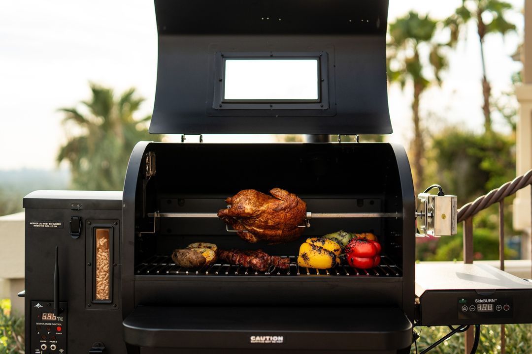A turkey is cooking on a grill with vegetables.