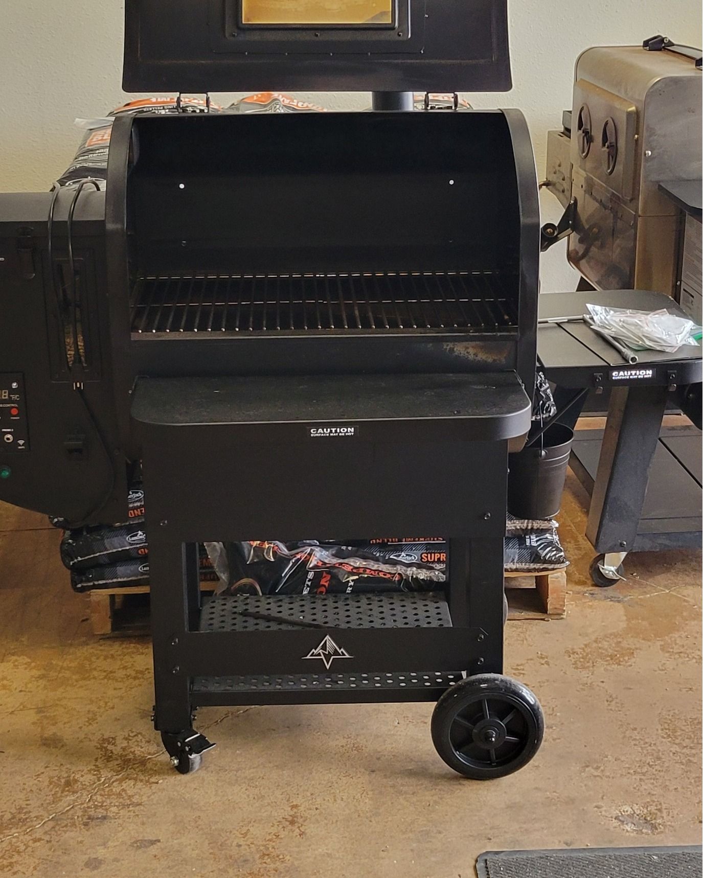 A black grill is sitting on a cart in a room.