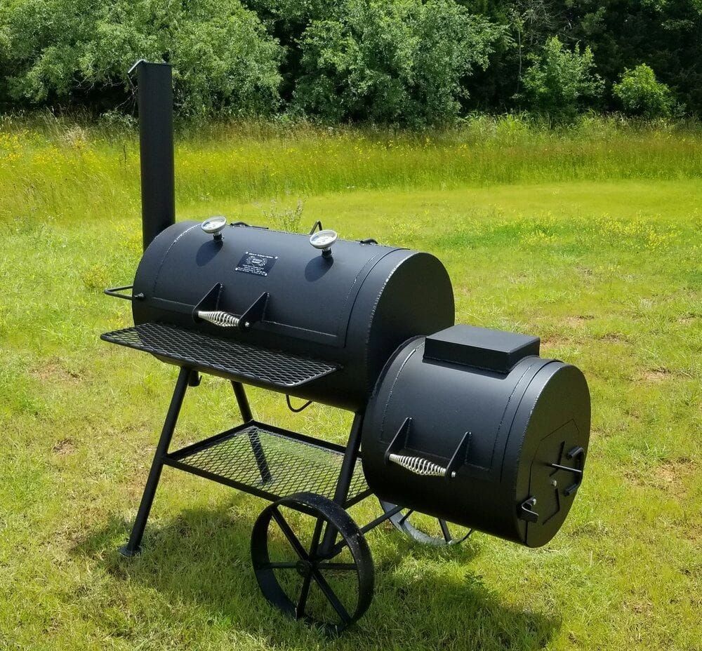 A black bbq grill is sitting in a grassy field