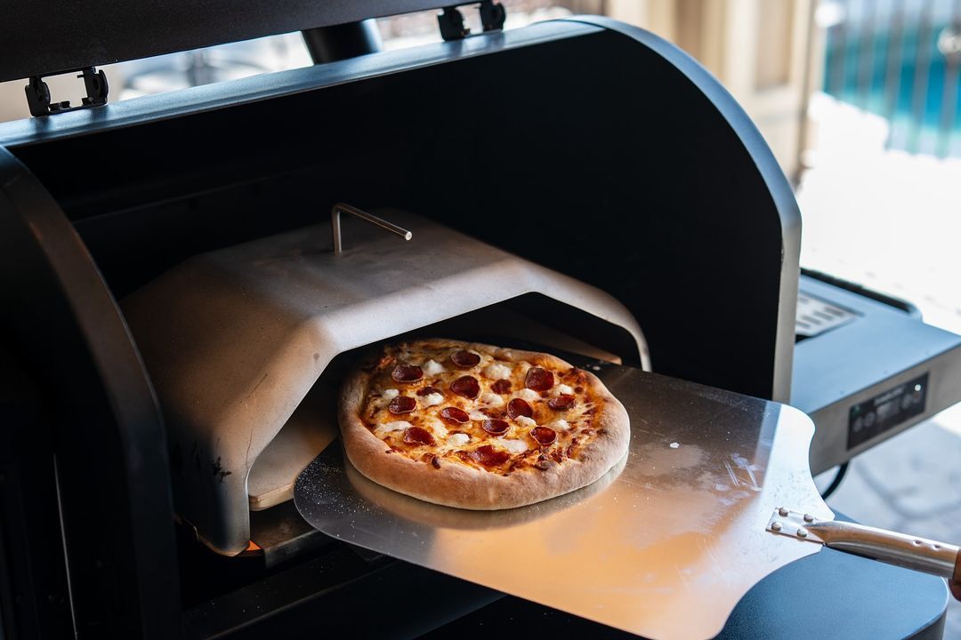 A pizza is being taken out of a pizza oven.
