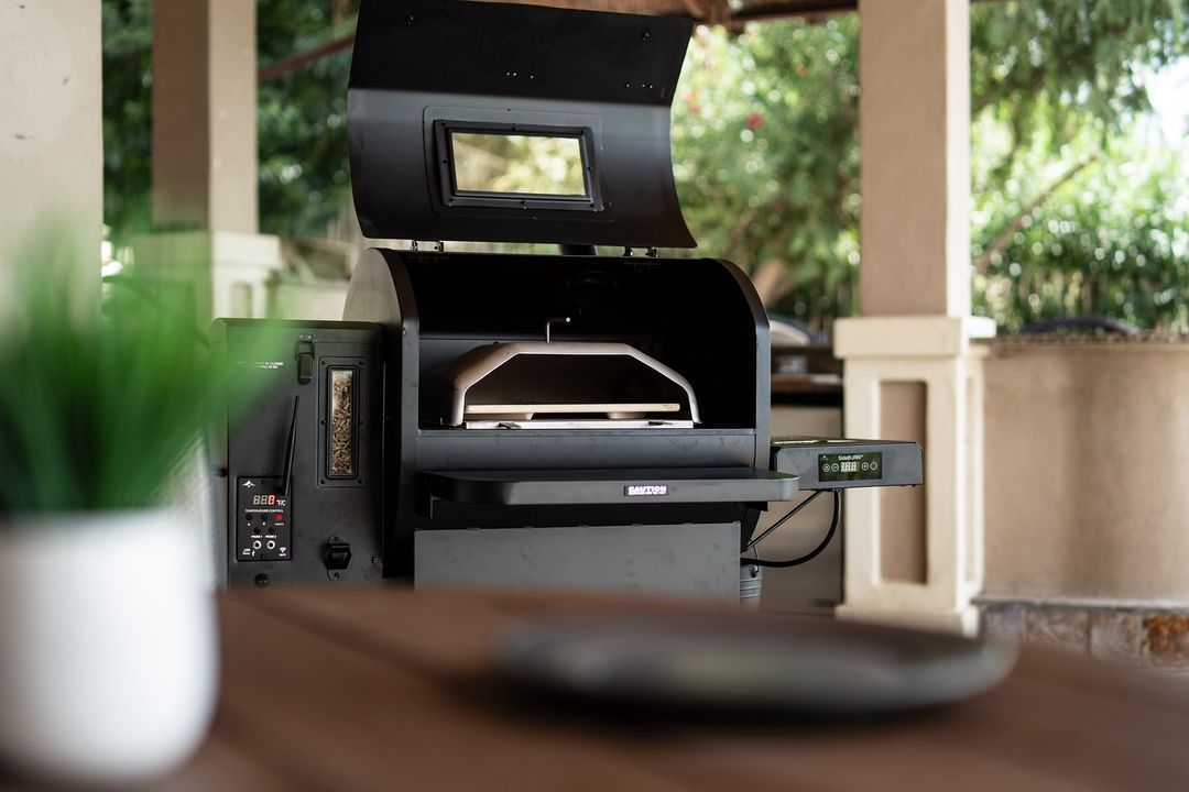 A grill is sitting on top of a wooden table on a porch.