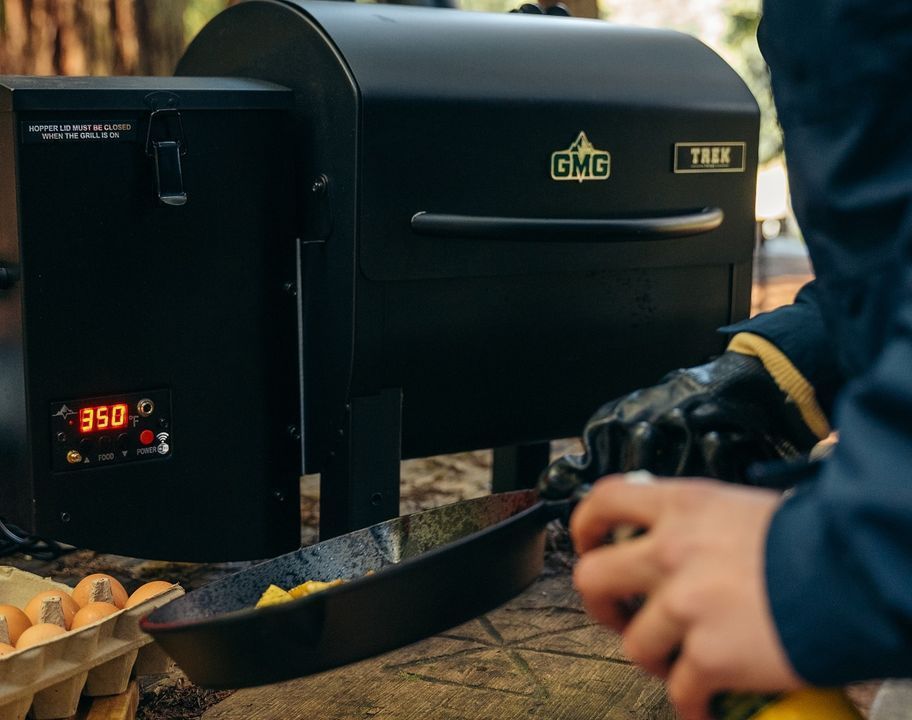 A person is cooking food in a pan on a grill.