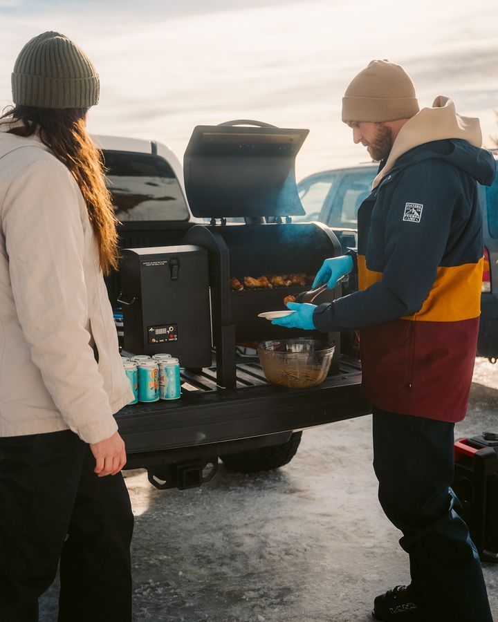 A man and a woman are preparing food in the back of a truck.