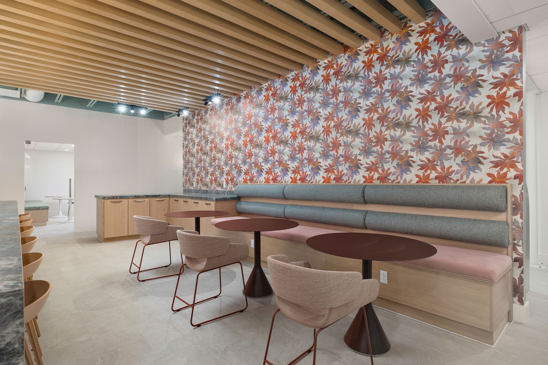 A room with tables and chairs and a floral wallpaper on the wall.