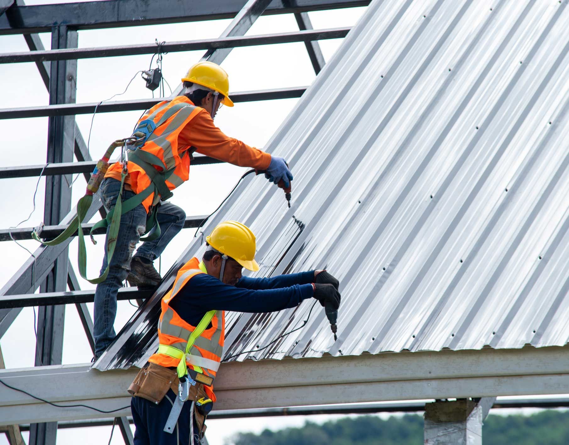Roofers installing emergency protective covering after storm.