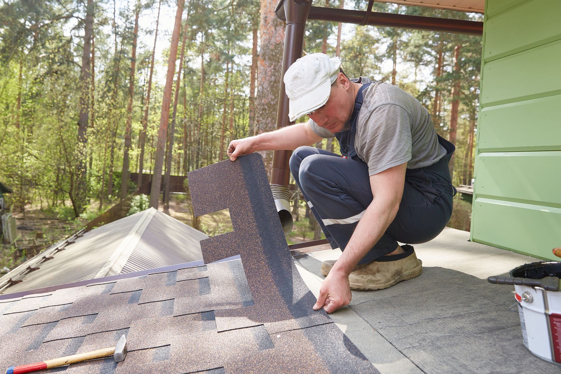 A contractor lays a roof of soft tiles on the roof of a country house.