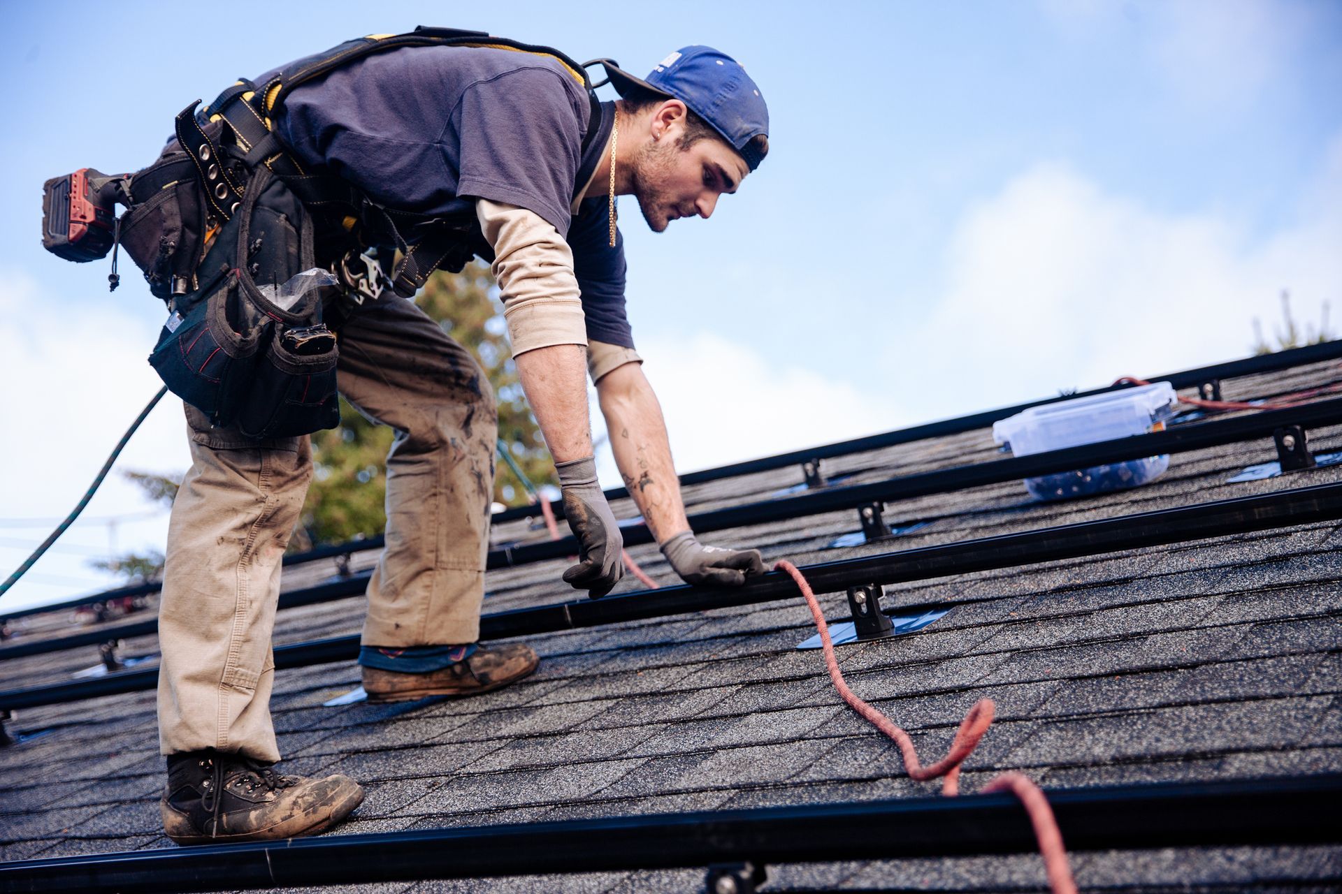 A man installs siding on a house with a drill, showcasing skilled craftsmanship & roofer services. A man installs siding on a house with a drill, showcasing skilled craftsmanship & roofer services.