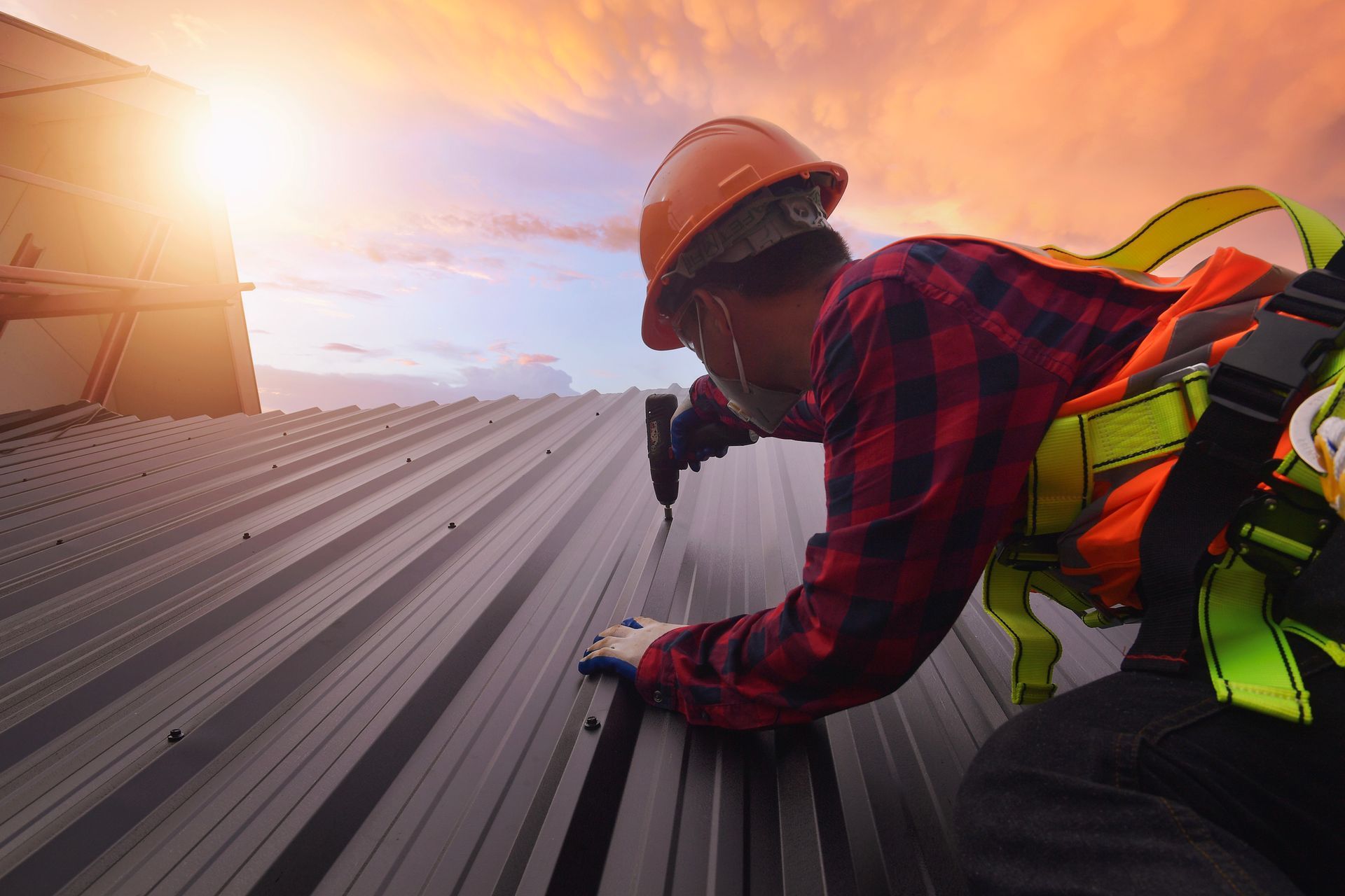 A roofer in safety gear and gloves, working diligently with skill on the roof.