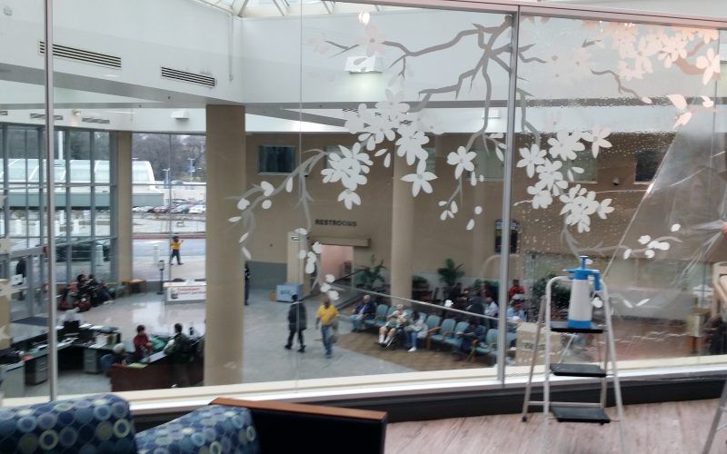 A ladder is sitting in front of a window with flowers on it