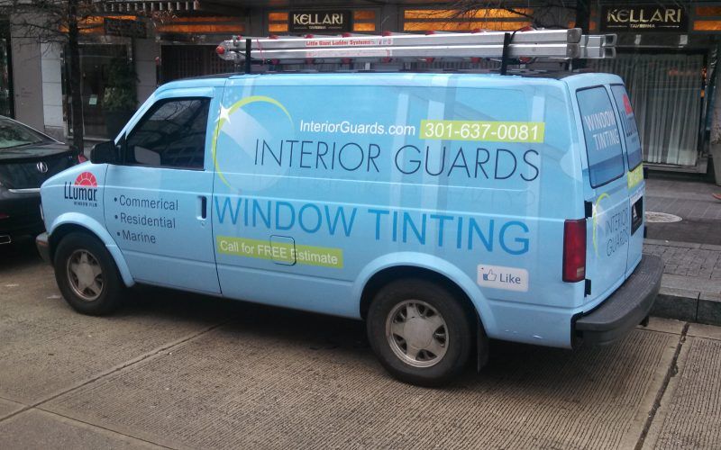 A blue van for interior guards window tinting is parked on the side of the road