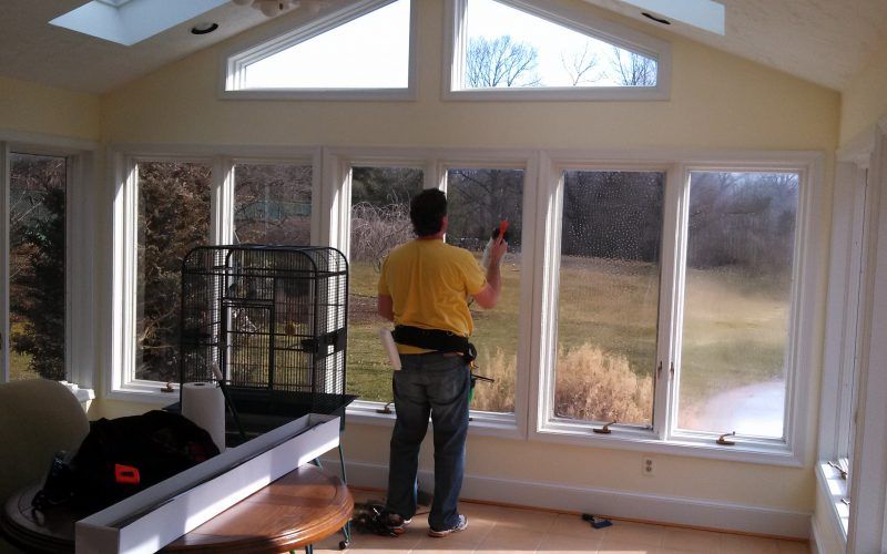A man in a yellow shirt is cleaning a window