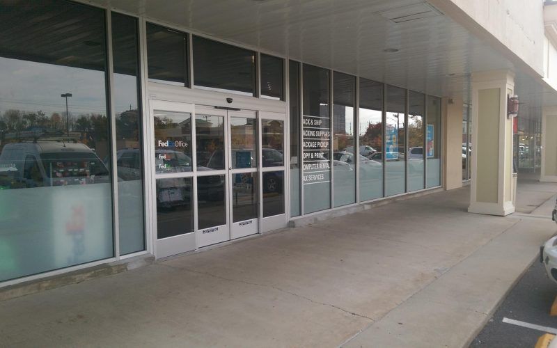 A store front with a lot of windows and a car parked in front of it.