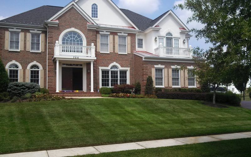 A large brick house with a lush green lawn in front of it