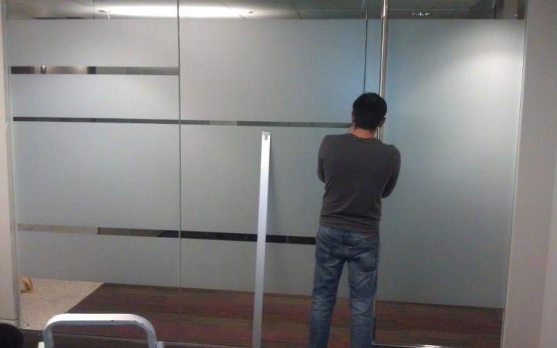 A man is standing in front of a glass wall.