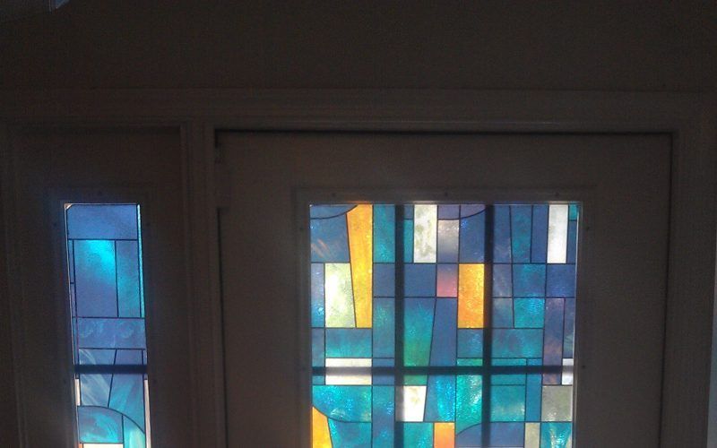 A stained glass window in a room with a white door.