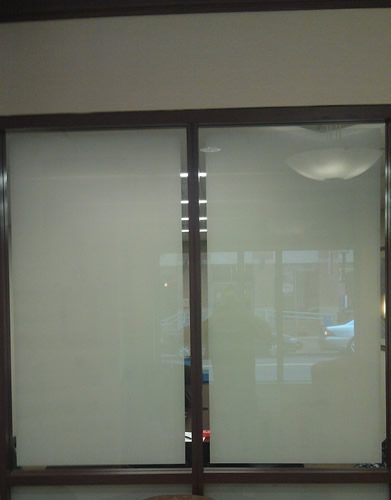 A large window with a brown frame and white blinds.