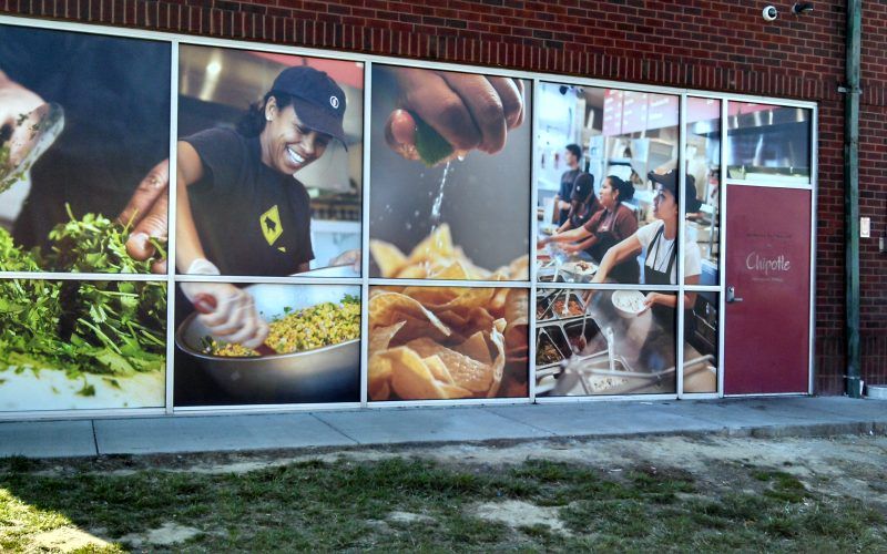 A brick building with a large window with pictures of food on it