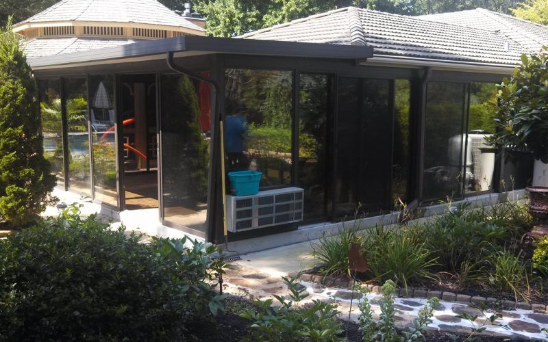 A house with a gazebo on top of it is surrounded by trees and bushes.