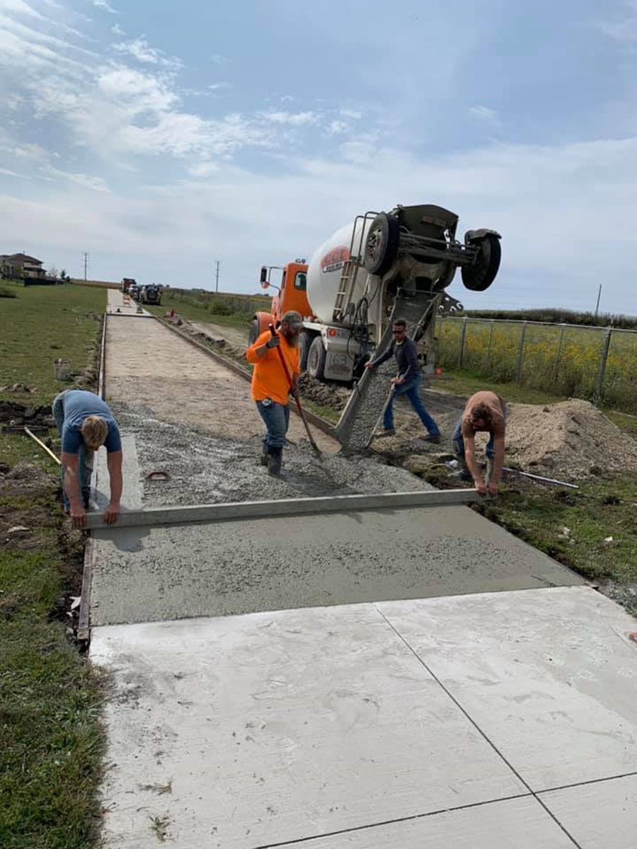A concrete truck is pouring concrete on a sidewalk.