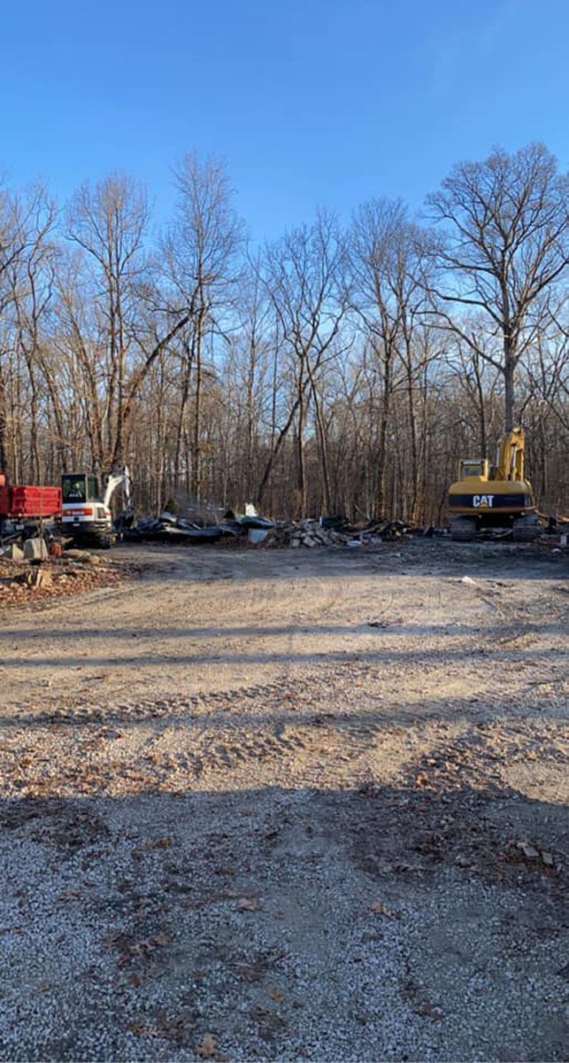 A construction site with a lot of trucks and trees in the background.