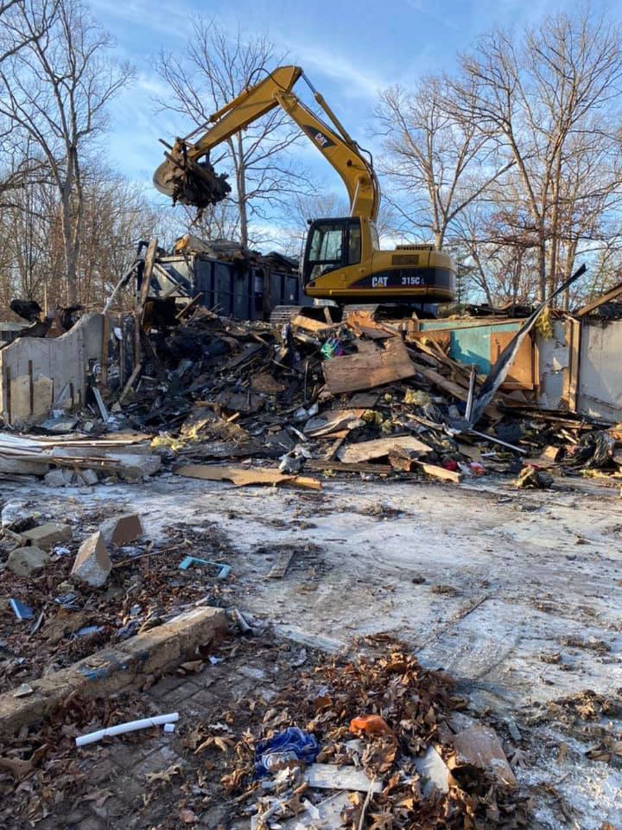 A bulldozer is demolishing a house in the snow.