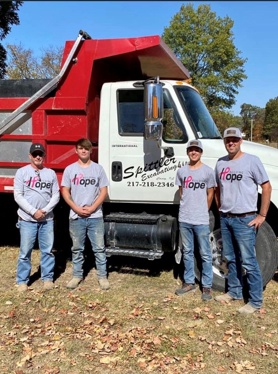A group of men are standing in front of a dump truck.