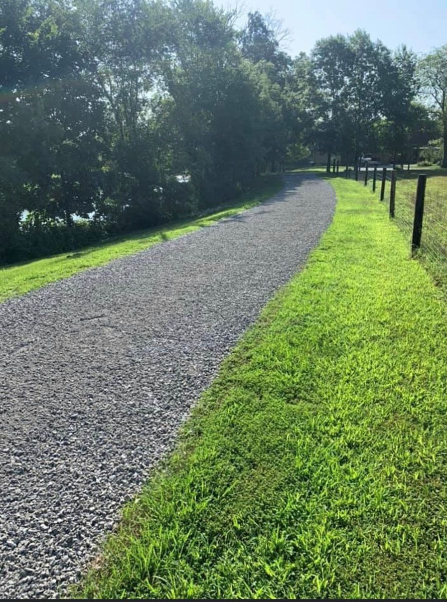 A gravel road going through a grassy field