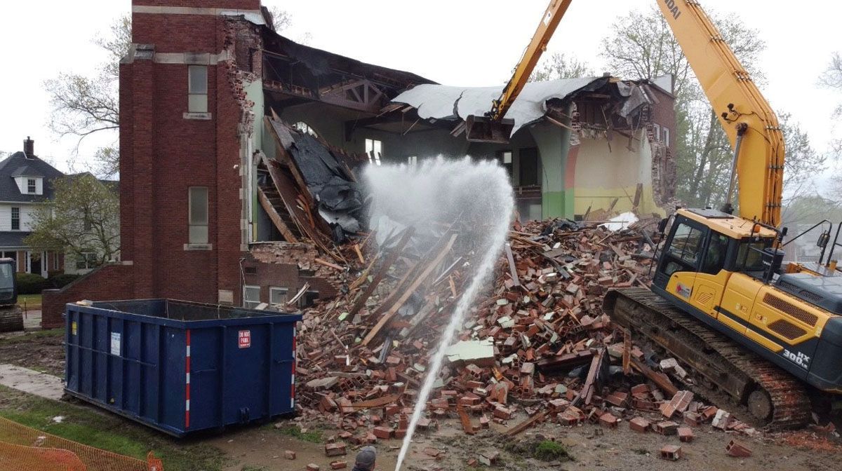A brick building is being demolished by a bulldozer.