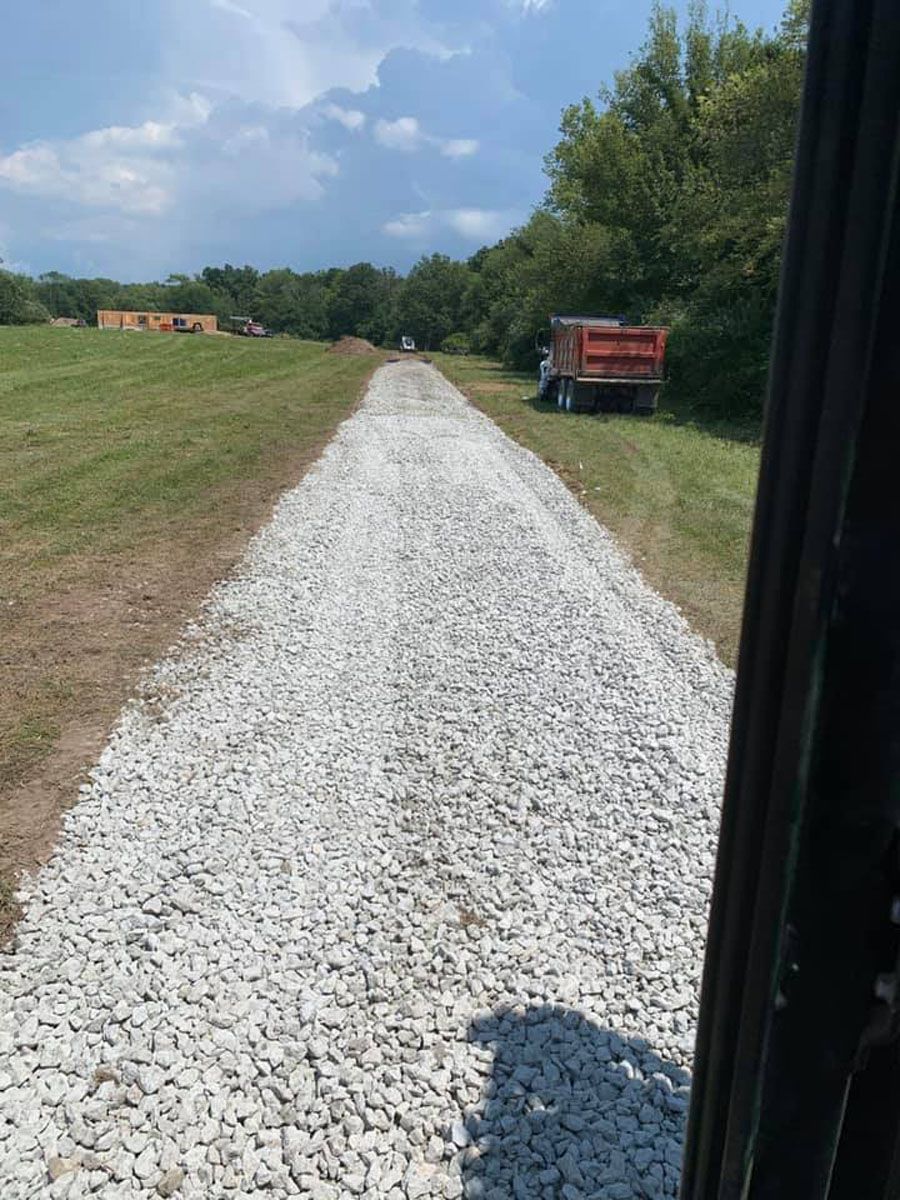 A truck is parked on the side of a gravel road.