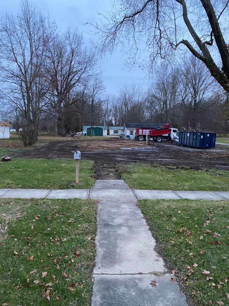 A dumpster is sitting on the side of the road next to a sidewalk.