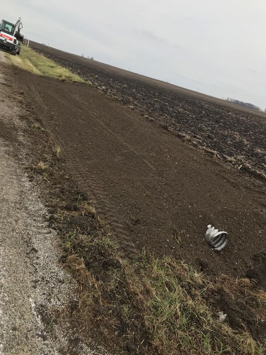 A truck is driving down a dirt road next to a field.