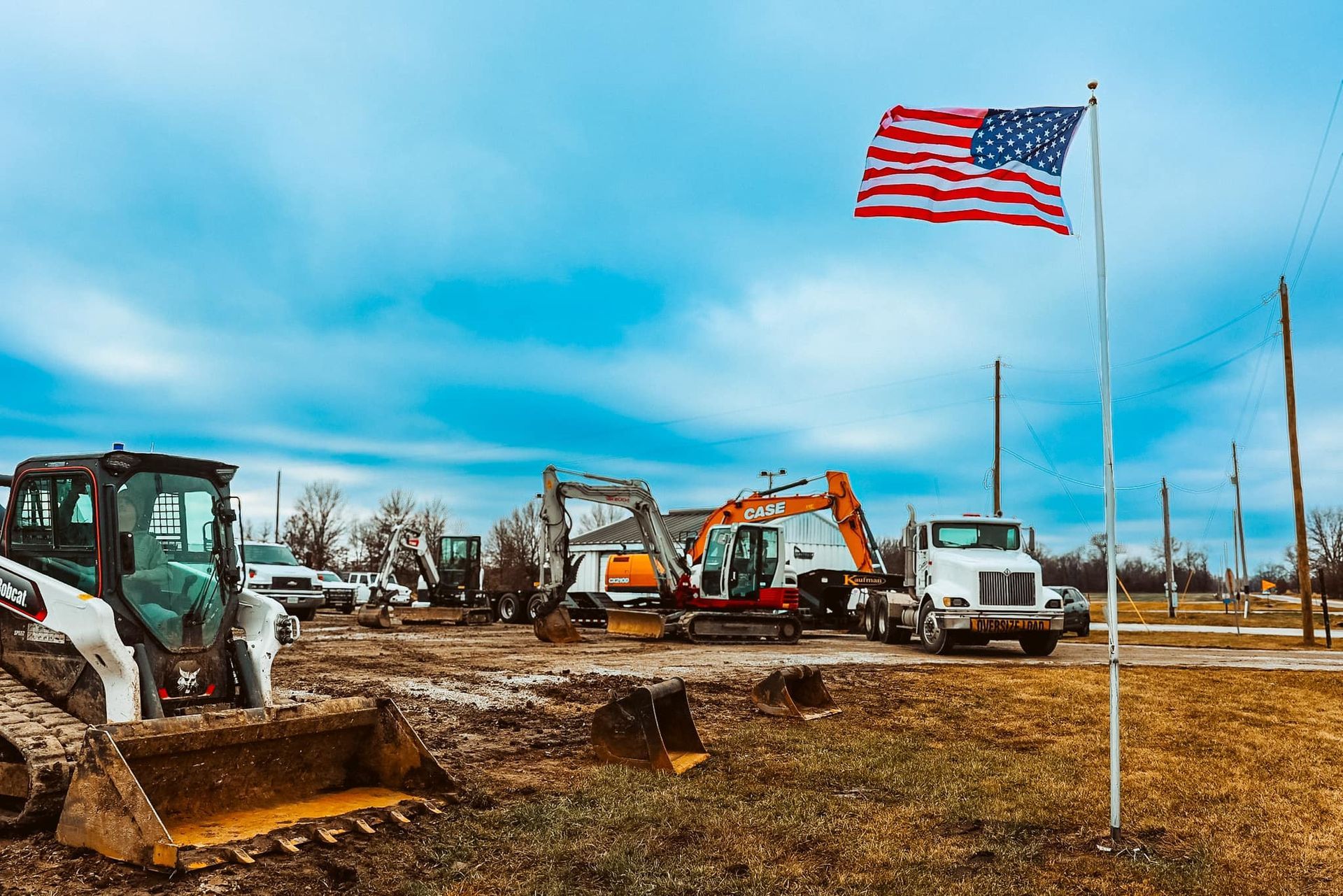 A large american flag is flying in front of a construction site.