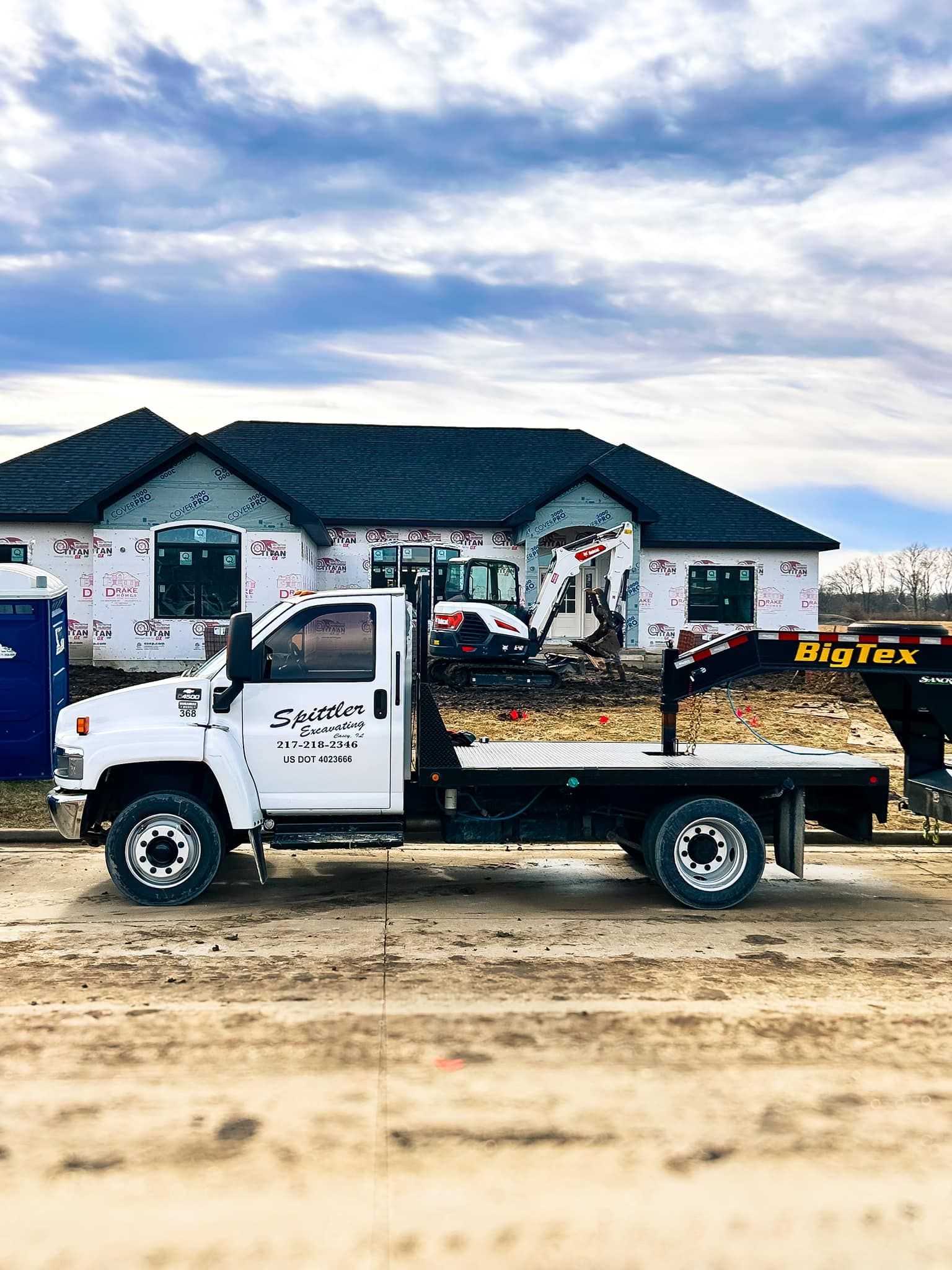 A tow truck is parked in front of a house under construction.