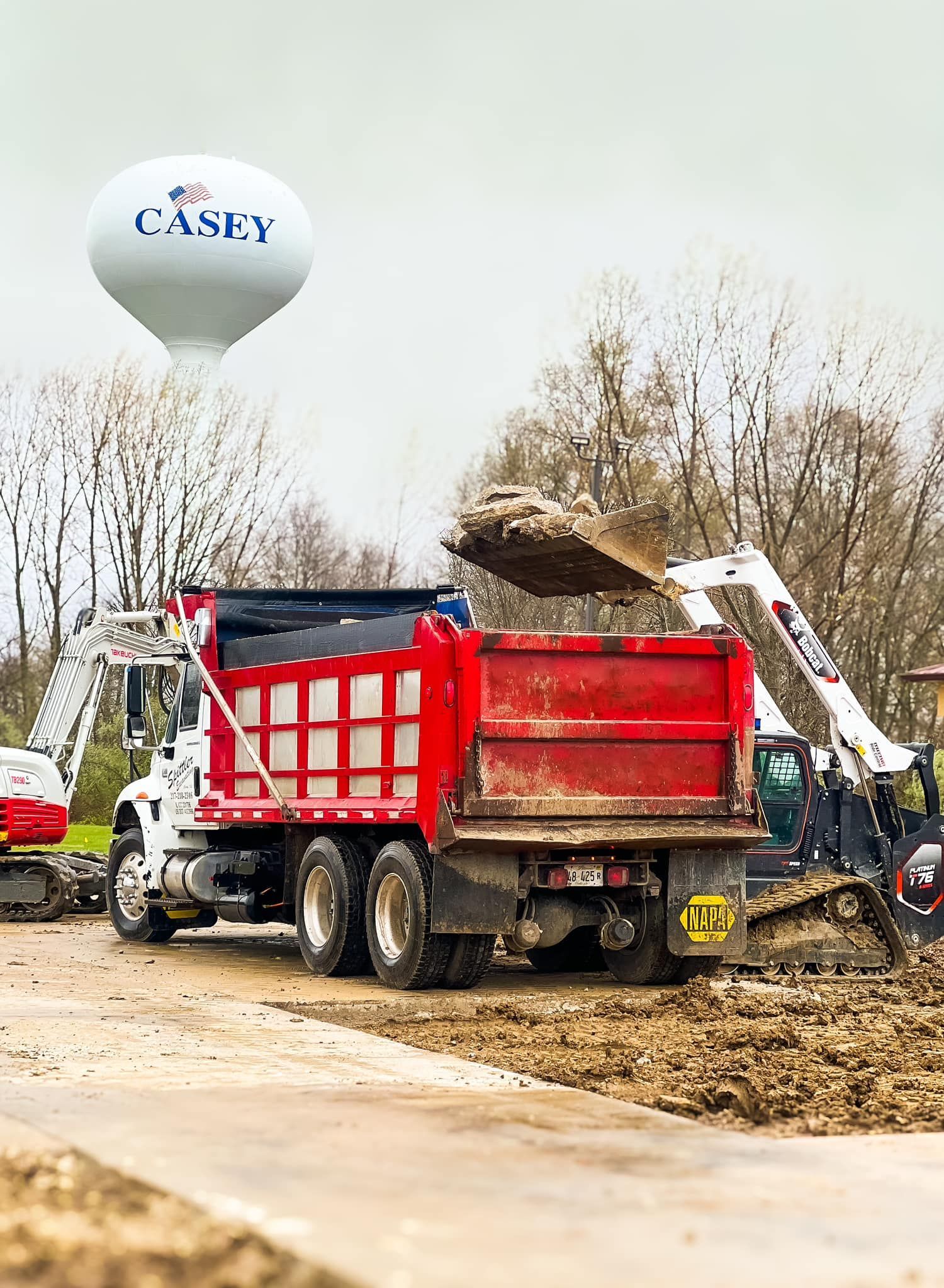 A dump truck is being loaded with dirt on a construction site.