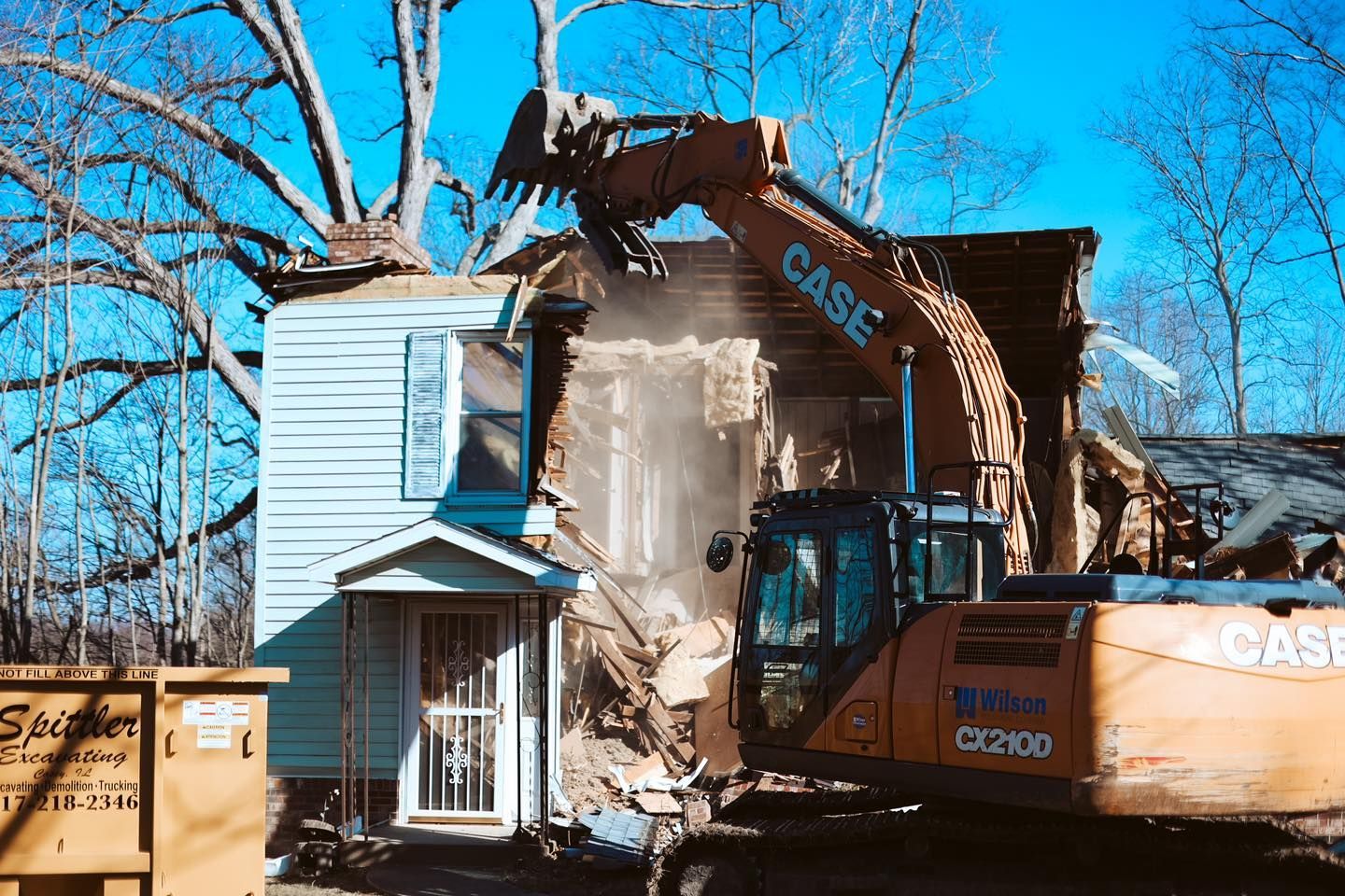 A house is being demolished by a case excavator.