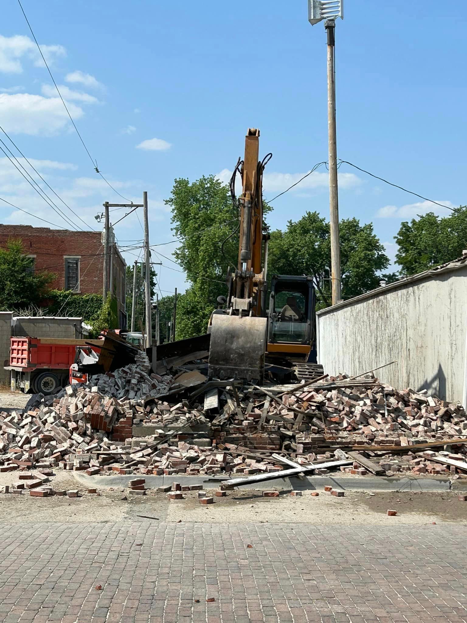 A bulldozer is demolishing a brick building