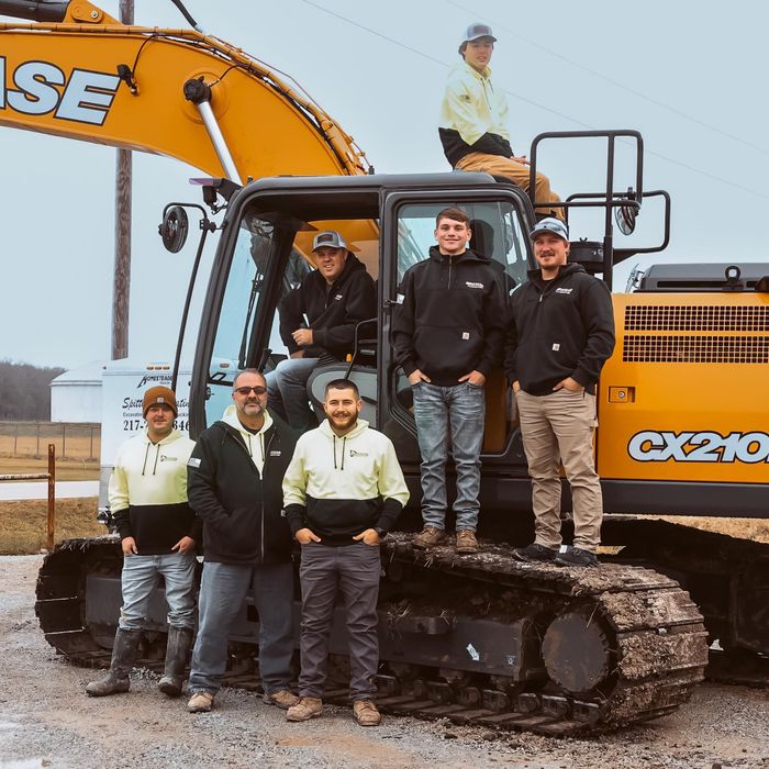 A group of men standing in front of a case cx210 excavator