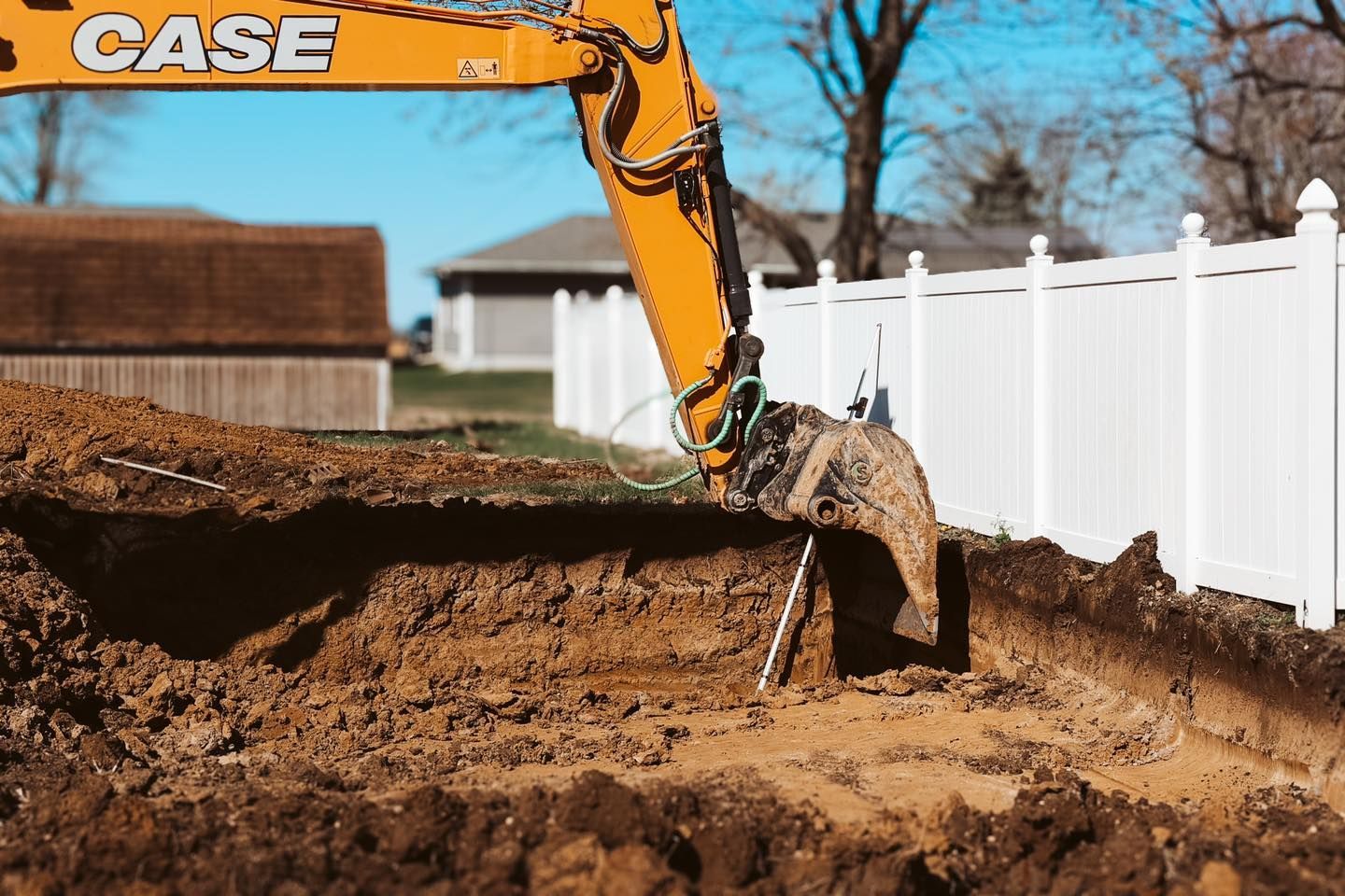 A yellow case excavator is digging a hole in the ground.