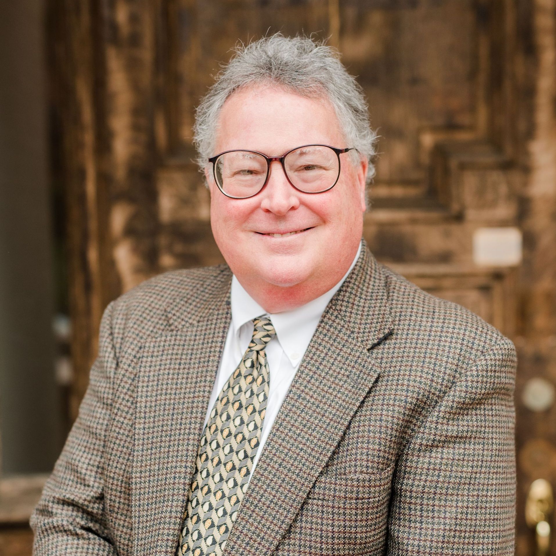 A man in a suit and tie is standing in front of a door.