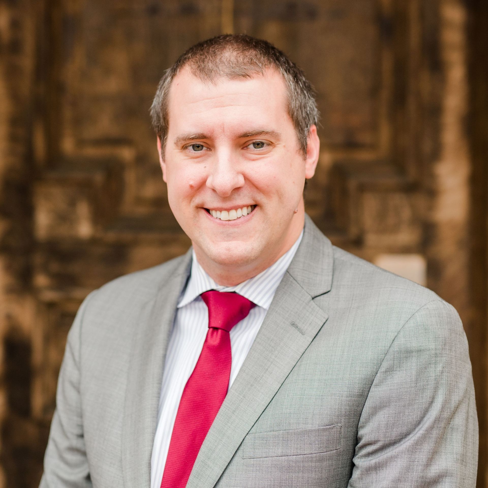 A man in a suit and red tie is smiling for the camera.