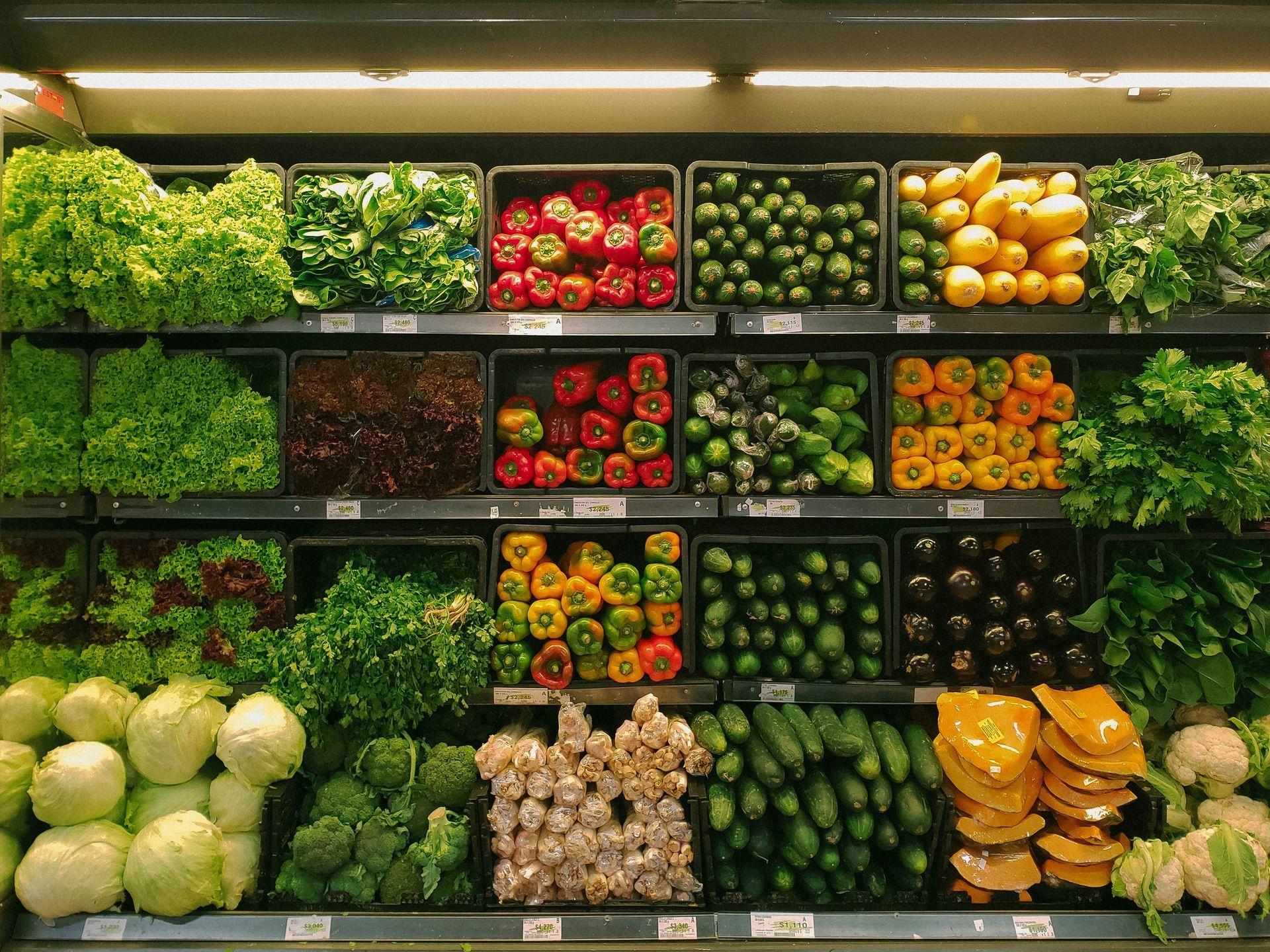 Produce section with assorted fruits and vegetables arranged in rows on shelves.