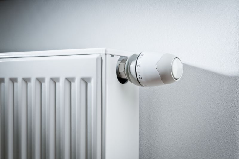 Radiatore bianco con valvola termostatica su una parete grigio chiaro