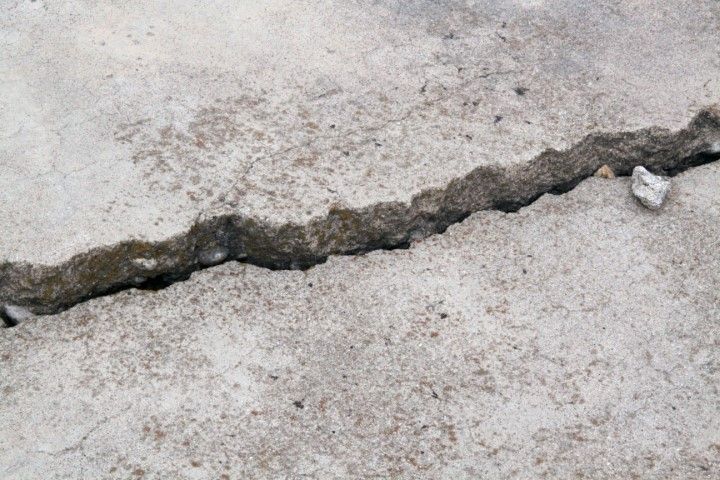 Close-up of cracked concrete surface with a deep fissure running across it.