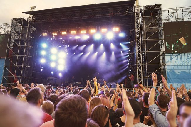 A crowd of people are standing in front of a stage at a concert.