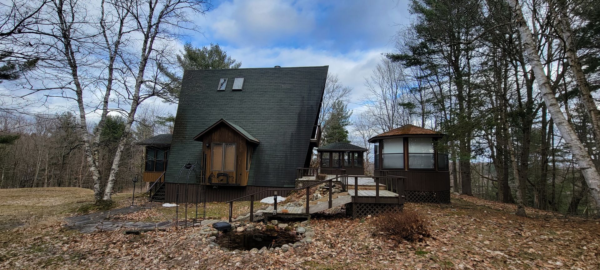 A small house is sitting on top of a hill in the middle of a forest.