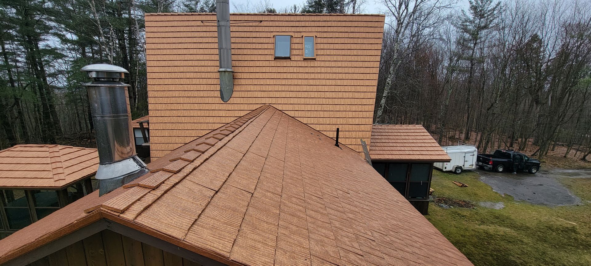 A house with a wooden roof is being built in the woods.