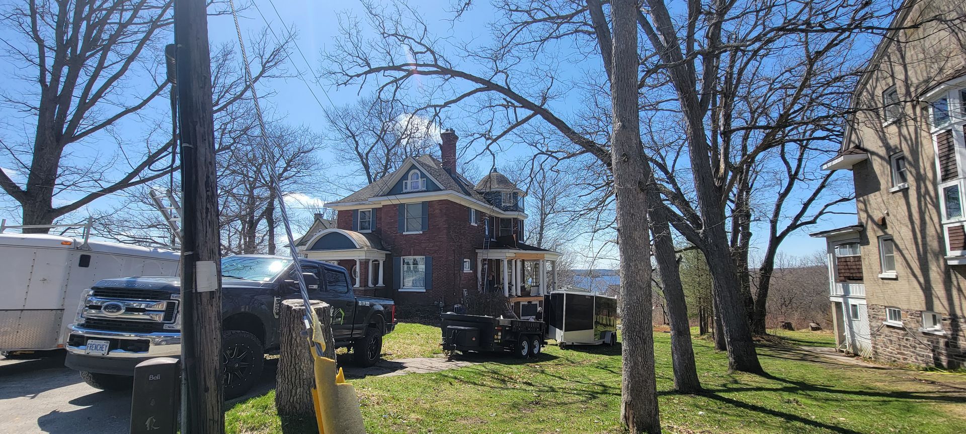 A brick house is surrounded by trees and a truck is parked in front of it.