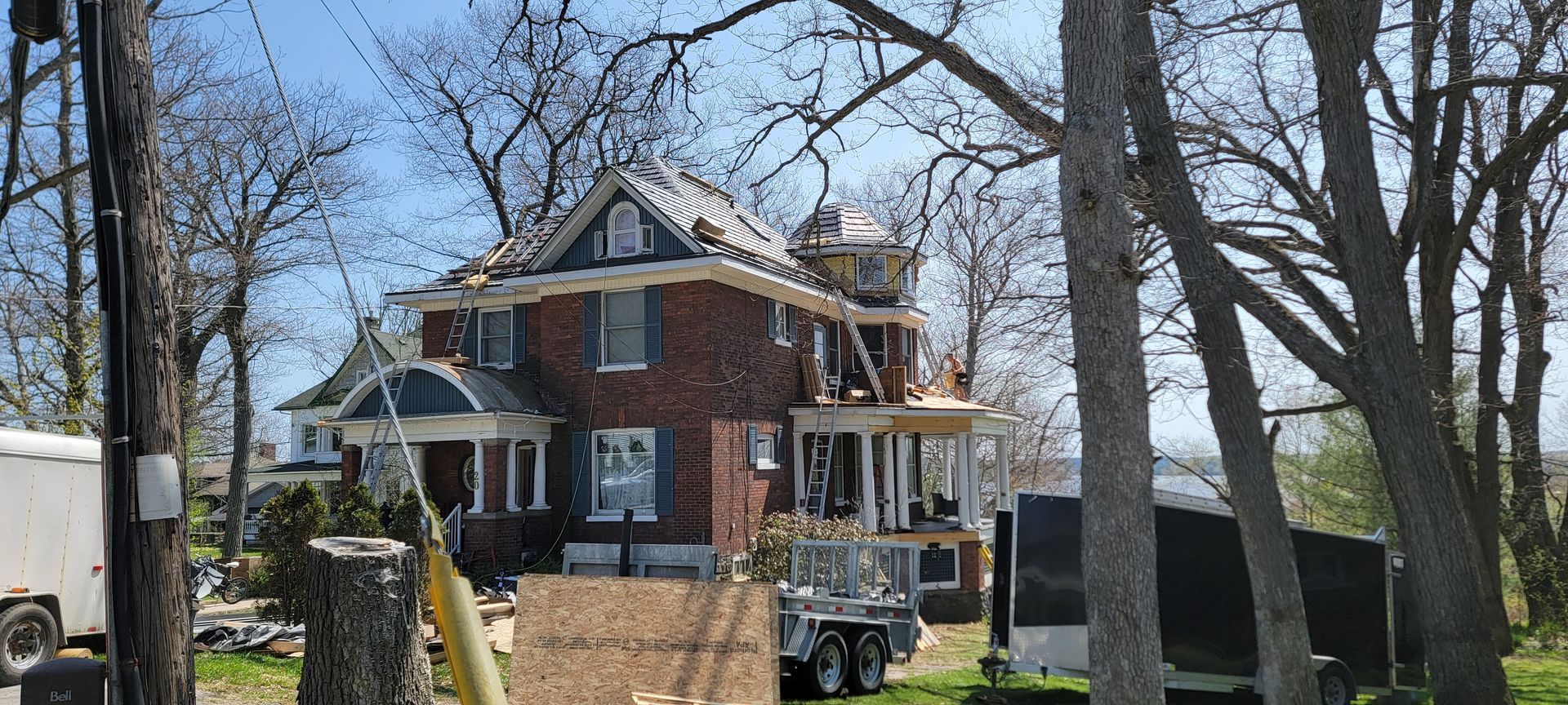 A large brick house is being remodeled with a new roof.