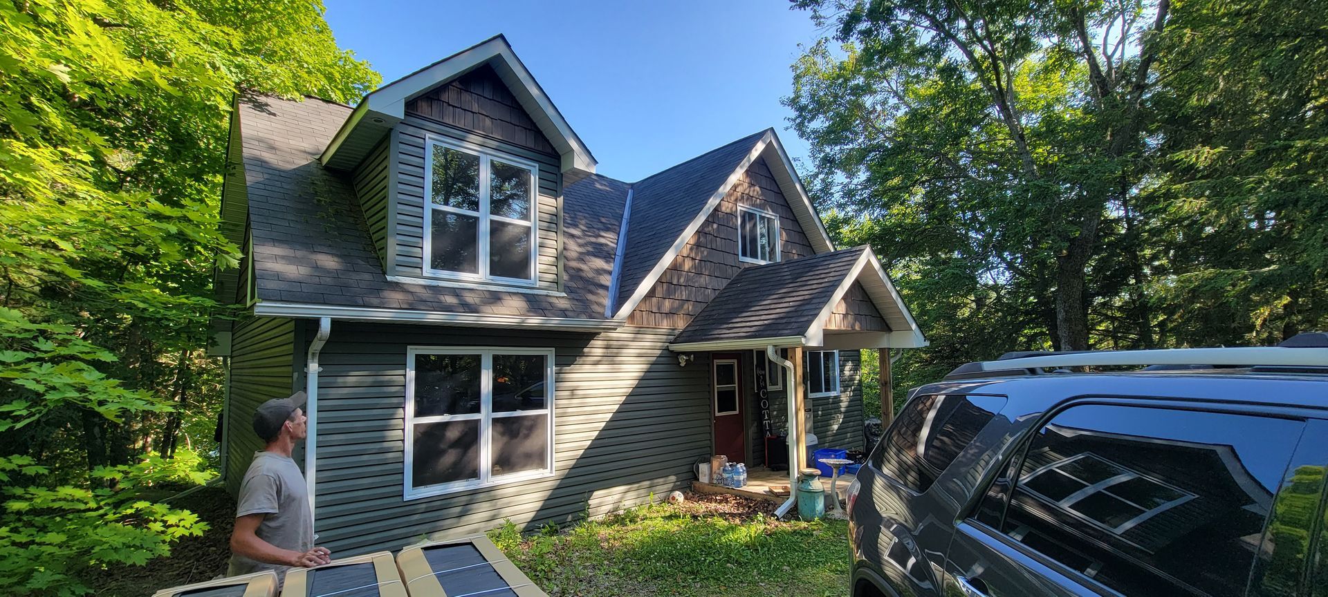 A man is standing in front of a house with a truck parked in front of it.