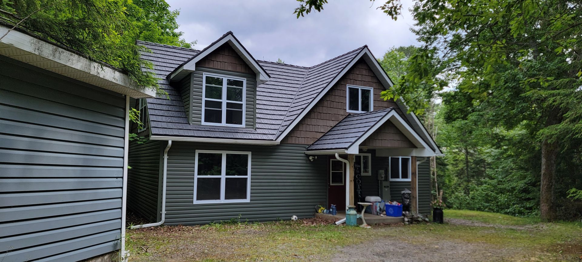 A large house with a garage in front of it is surrounded by trees.